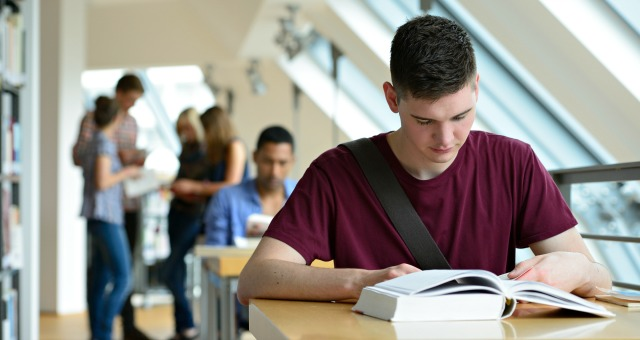 A stock photo of a student studying in a library.